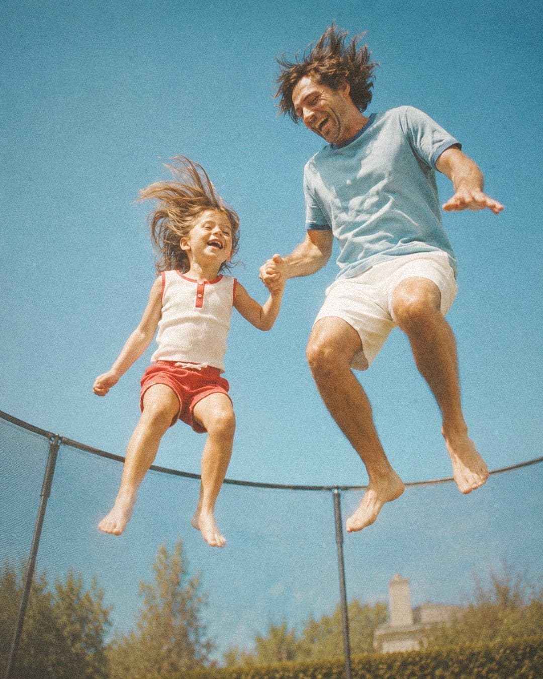 Father and daughter jumping on a backyard trampoline in Auckland